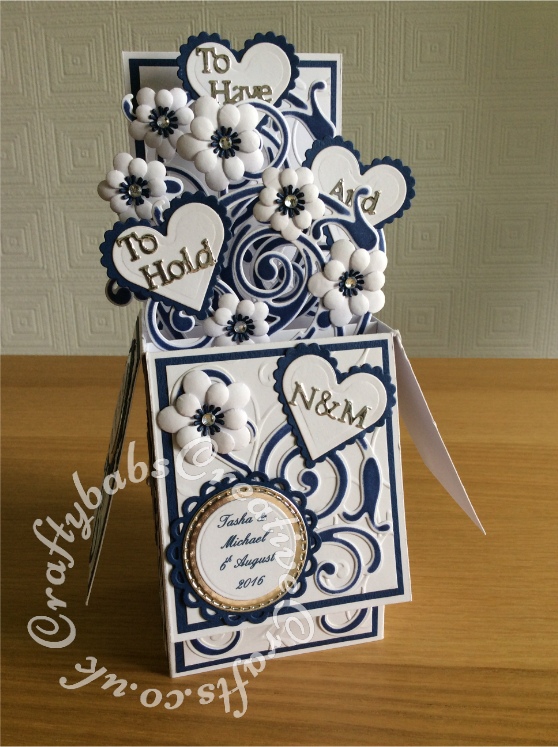 Pop up Wedding card made using a number of dies including; Spellbinders nesting plain and scalloped hearts dies, Cheery lynn flowers dies, Anna griffin flourish scroll die, spellbinders lacey circles dies, Crea Nest lies no 33 dies, leabilities frame square curve die set (for small flourishes). Joy cut & emboss wedding die set, Background embossed with Xcut A4 folder. Die cuts inked whilst in die in matching distress ink (Chipped Sapphire) - craftybabscreativecrafts.co.uk