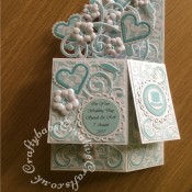 Pop up Wedding card made using a number of dies including; Spellbinders nesting plain and scalloped hearts dies, Cheery lynn flowers dies, Anna griffin flourish scroll die, spellbinders lacey circles dies, Crea Nest lies no 33 dies, leabilities frame square curve die set (for small flourishes). Joy cut & emboss wedding die set, Nellies nesting stitched squares dies, Background embossed with distress ink applied to folder using embossaliscious a4 folder. die cuts inked whilst in die in matching distress ink (Broken China). - craftybabscreativecrafts.co.uk