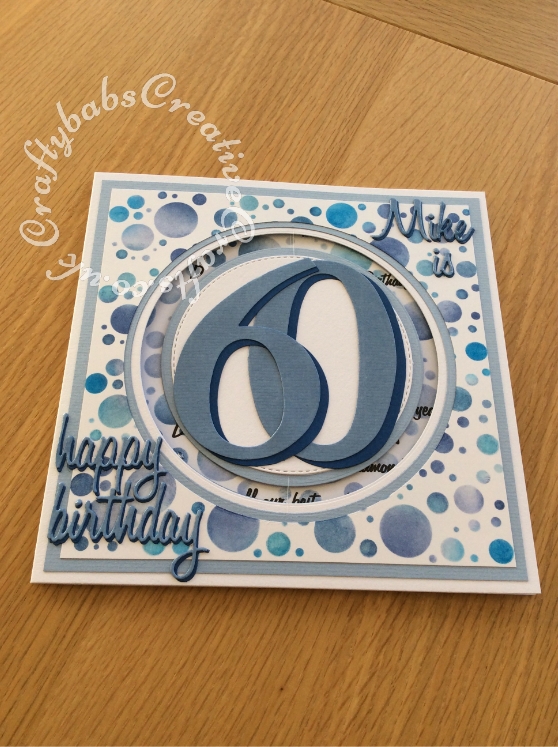 8" x 8" 60th Birthday Spinner card made using various dies including; 660223 Sizzix Thinlits Die Set 13PK - Celebration Words Script by Tim Holtz, 662228 Sizzix Thinlits Die Set 69PK - Script, Upper & Lower Case dies by Tim Holtz, 656617 Sizzix Bigz Sassy Serif Numbers dies, Tattered lace Essentials nesting circles dies and Crealies DOUBLE STITCH Die Set No.33 CIRCLE Cutting Dies XXL33 , Numbers, words and letters cut from 2 shades of blue card and heat embossed with clear embossing powder Background inked through stencil with various shades of Blue Tim Holtz distress inks, 'Fabulous' Sentiment stamped using FOREVER-FRIENDS-OPULENT-A5-Clear-Stamp-Set-Docrafts. Highlights and accents added using Spectrum Noir Sparkle clear overlay pen. - craftybabscreativecrafts.co.uk