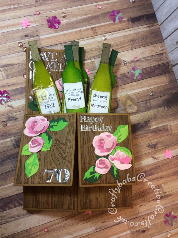 Pop up 70th birthday card made using a variety of dies including; Tattered lace sentiment dies from 3diemensions sets paper-pieced to make appropriate words, Custom made wooden wine bottle dies, Zip-e-mate thin metal wine glass & bottle dies (for acetate glass), Spellbinders shapeabilities dies Etched Alphabet for numbers, Rose flurries dies Bottle labels printed from 'The Wine Buffs' cd rom. Mats for card base embossed with wood grain embossing folder and inked with distress inks. Wine bottle glossed with Glossy Accents. - craftybabscreativecrafts.co.uk