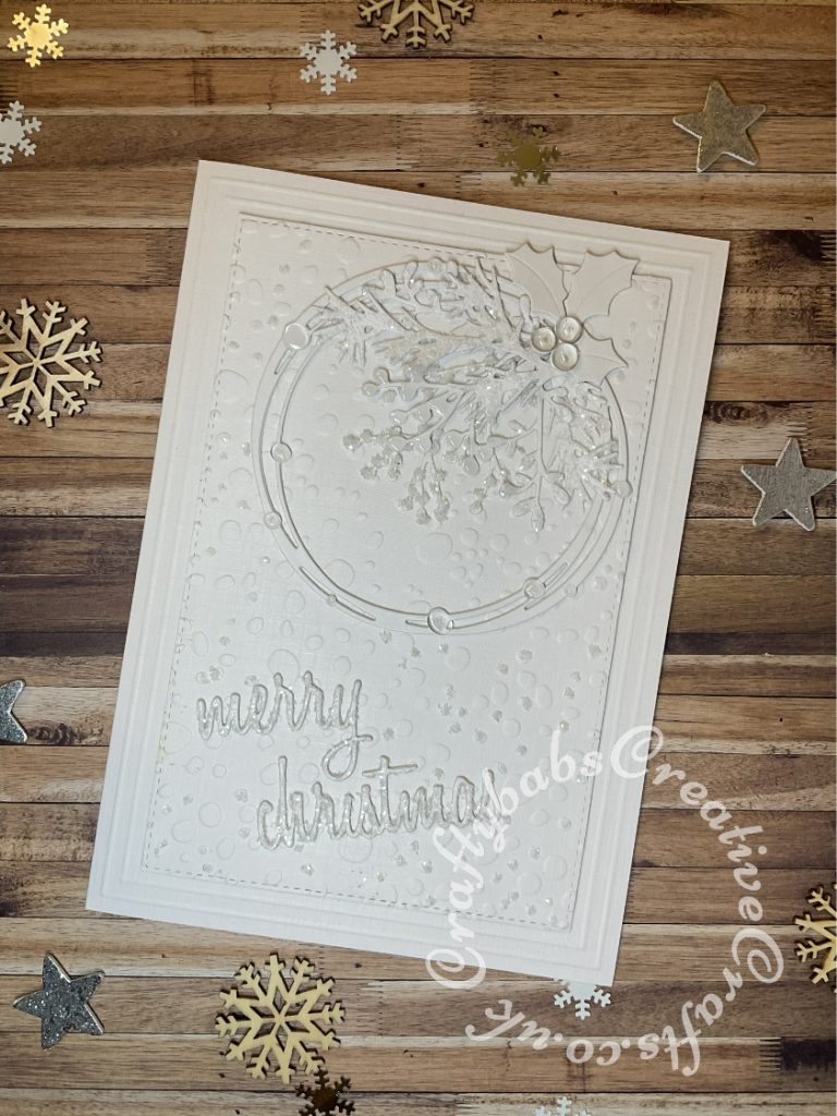 White on white Christmas card inspired by a card on Pinterest https://www.pinterest.co.uk/pin/555983516510989238/ Made using various dies including:- Starlight Circle Die Set, Skip to the beginning of the images gallery Sizzix Thinlits Die Set 17PK - Holiday Words: Script, Sizzix - Tim Holtz - Alterations Collection - Thinlits Dies - Holiday Greens, Marianne holly die and Crafters companion textures embossing folder - rain. - craftybabscreativecrafts.co.uk