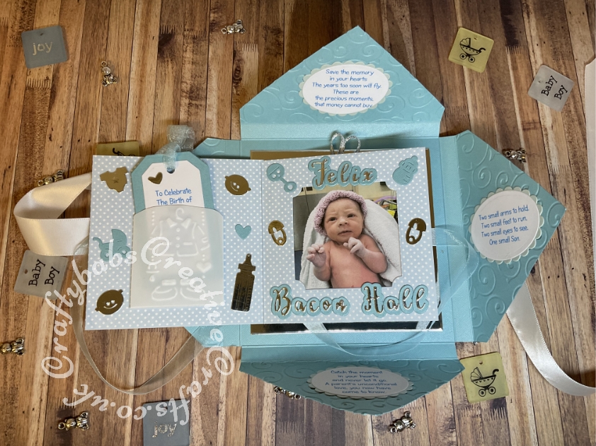 Baby Boy Birth keepsake made using a variety of dies including Tattered Lace Essentials nesting Notched squares dies, Marianne Design Collectables Cutting Dies - Eline's Babies Col1479, Marianne designs Creatables baby feet dies, MEMORY BOX 98867 "Baby Bottles" die, Memory box Baby clothes die 98625, Quickutz nesting Tag dies, Lettering created using Gemini Die Set Expressions Uppercase Alphabet, Gemini Die Set Expressions Lowercase Alphabet, Ellison thick cutz envelope die, Spellbinders nesting plain & scalloped oval dies, Parchment pocket made using an envelope template stencil, baby clothes and baby words embossed using brass stencils, outer cover embossed using couture creations intrinsic embossing folder. - craftybabscreativecrafts.co.uk