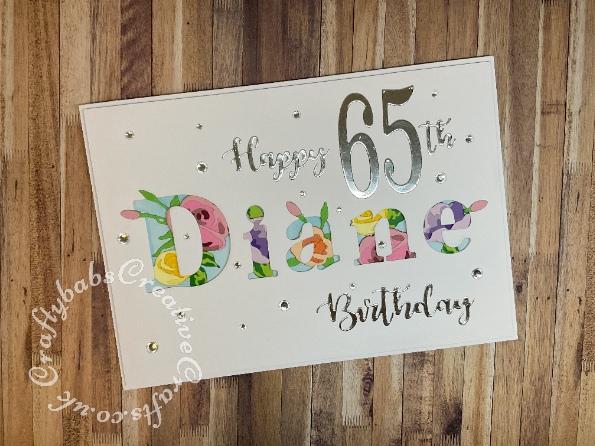 Birthday card made using a number of dies including 'Happy Birthday' sentiment from Gemini cut in sentiments, numbers from Sizzix Thinlits Die Set Fabulous Birthday Numbers by Debi Potter, layered flowers dies and Card Making Magic Die Set Solid Alphabet Letter by Christina Griffiths. -craftybabscreativecrafts.co.uk