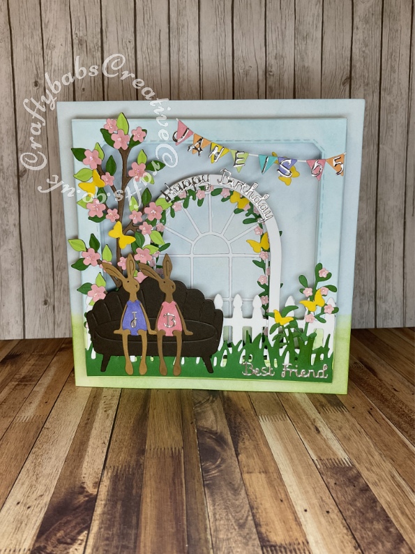 3D shadow box effect card made using various dies including: Surprise Creations Double stitched nested square dies for aperture, Cheery Lynn Designs FRM142 Window B and Sizzix Framelits Nested Arch dies for flower, arch, Go Kreate Fence die, Xcut English Countryside bprders grass border die, Creative Expressions Sue Wilson Finishing Touches Spring Foliage Dies, Memory box butterflies die, unbranded bunny rabbit die, Sizzix thinlits die set 664494 Cosy night in for garden seat, Hunkydory Moonstone sentiment dies. Sizzix thinlits die set 665345 Woodland celebration for bunting and Die-Versions MARKER MICRO Font Die. - craftybabscreativecrafts.co.uk