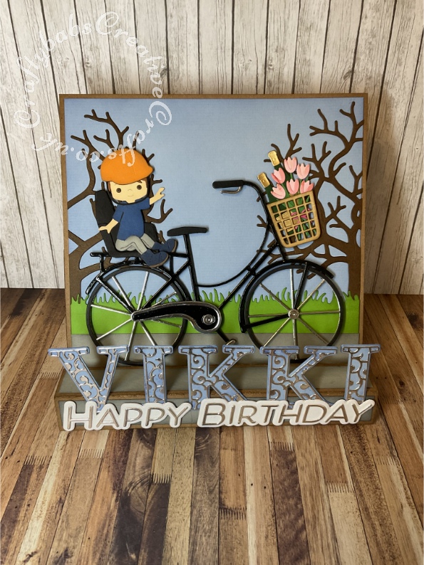 Large Personalised 8" x 8" Square box easel card made using various dies including: Spellbinders Big Bicycle by Bibi Cameron, Unbranded child die set ( from horse riding set ), Xcut A5 Die Set (15pcs) - Family Tree, Spellbinders large die of the month May 2022 for 'Happy Birthday', X-Cut Grass border die and Card Making Magic Upper case alphabet and overlay dies. - craftybabscreativecrafts.co.uk