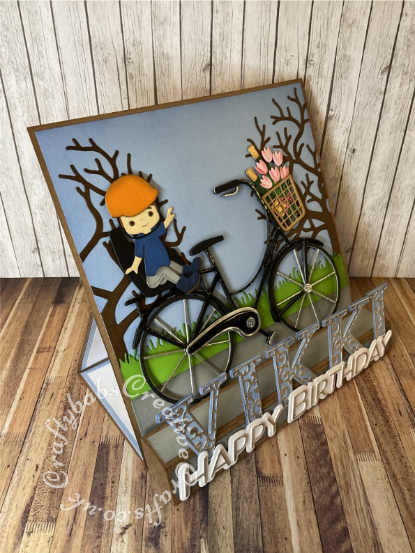 Large Personalised 8" x 8" Square box easel card made using various dies including: Spellbinders Big Bicycle by Bibi Cameron, Unbranded child die set ( from horse riding set ), Xcut A5 Die Set (15pcs) - Family Tree, Spellbinders large die of the month May 2022 for 'Happy Birthday', X-Cut Grass border die and Card Making Magic Upper case alphabet and overlay dies. - craftybabscreativecrafts.co.uk